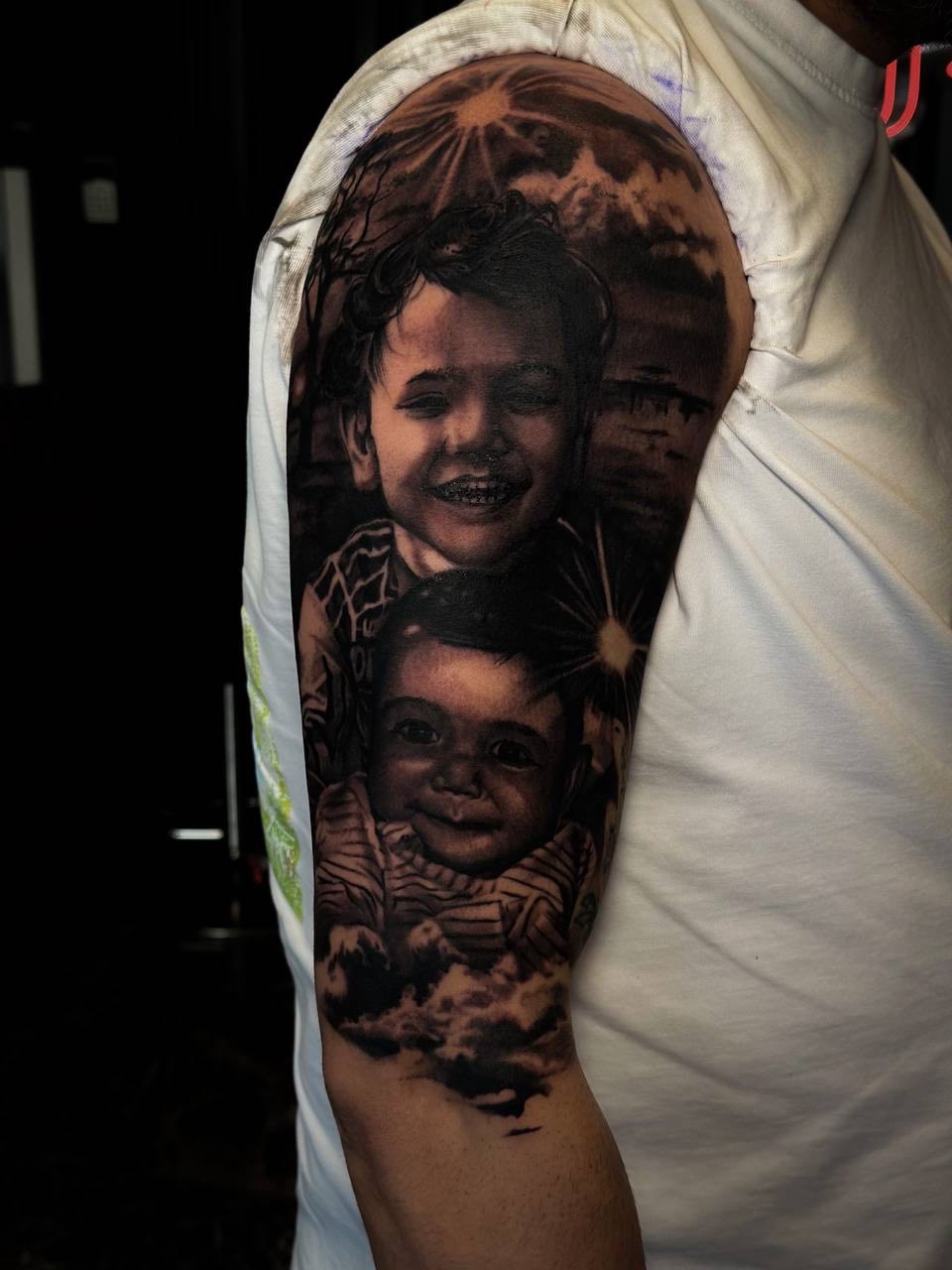 Realistisches Schwarz-Grau-Portrait-Tattoo von Kindern am Oberarm