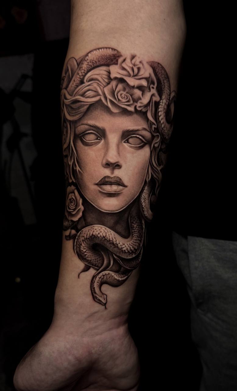 Black-and-Grey Medusa-Tattoo am Unterarm; realistisches Medusa-Portrait mit Schlangen und Rosen im Haar