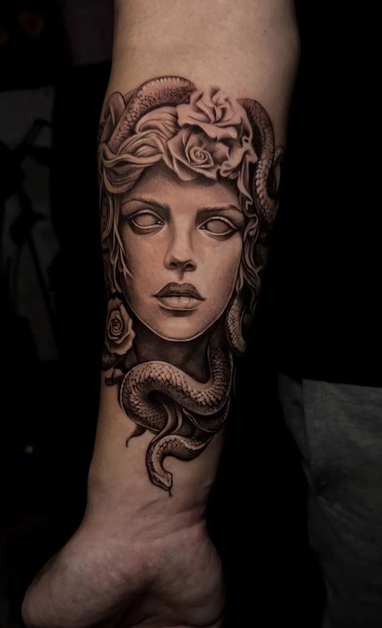 Black-and-Grey Medusa-Tattoo am Unterarm; realistisches Medusa-Portrait mit Schlangen und Rosen im Haar