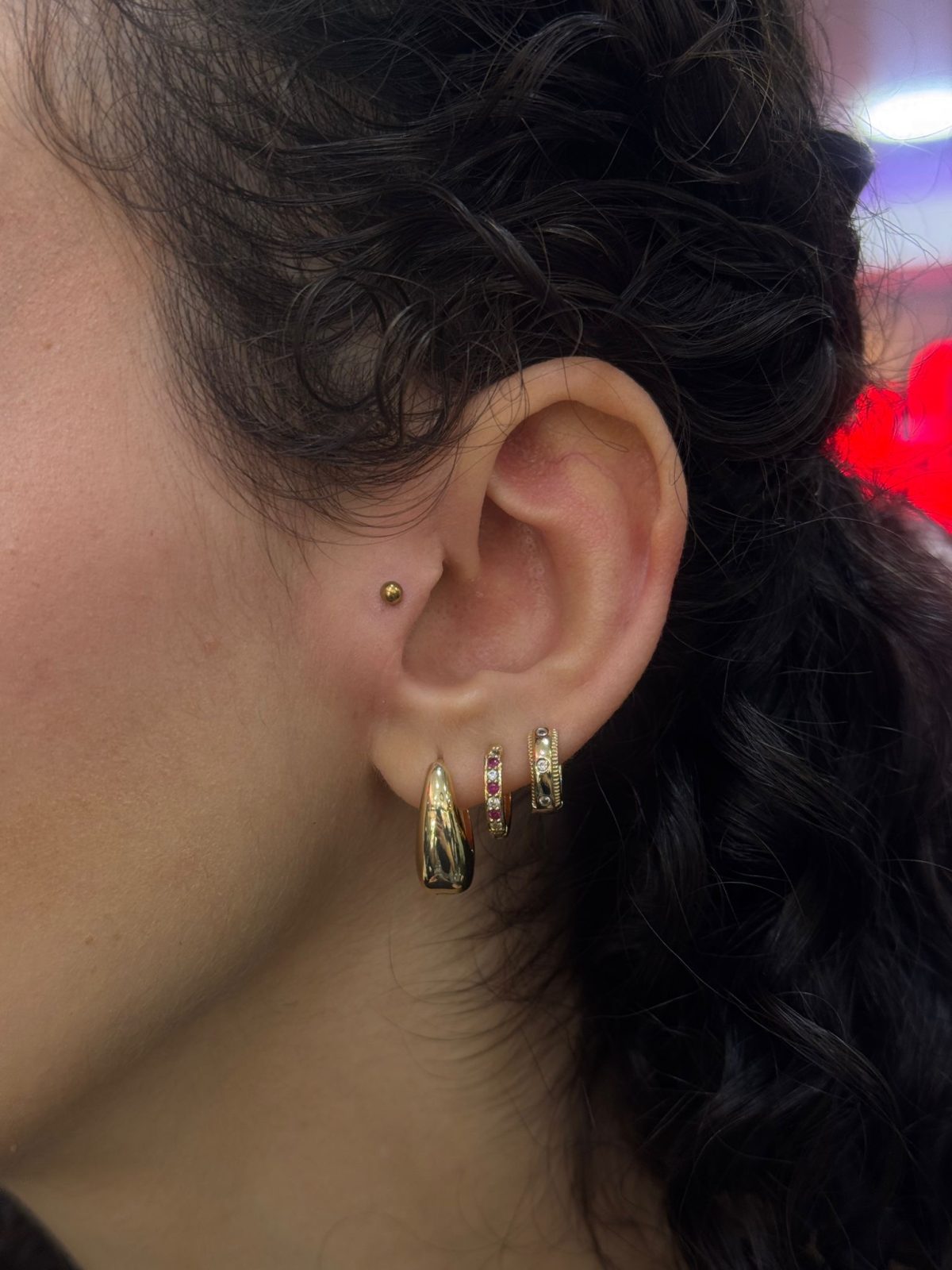 Gold titanium piercing jewellery on earlobe and tragus