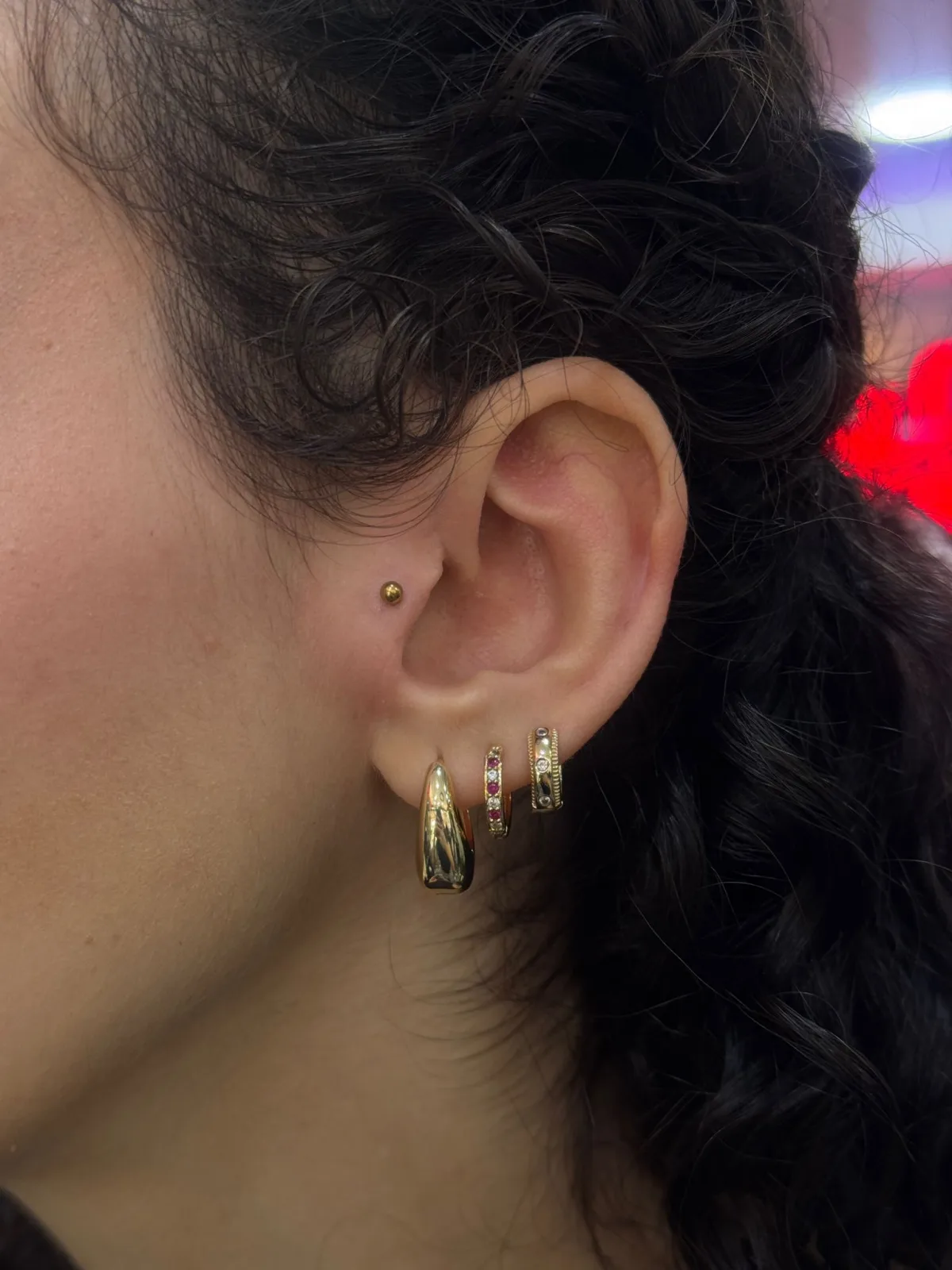 Gold titanium piercing jewellery on earlobe and tragus